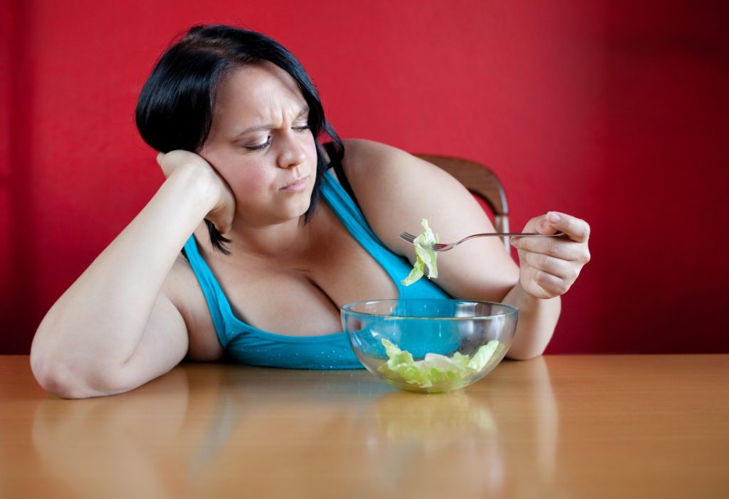 Unhappy Overweight Woman With Her Meal, A Bowl With A Few Leaves